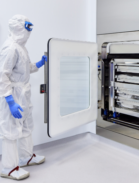 A worker in a white clean suit opening a machine door